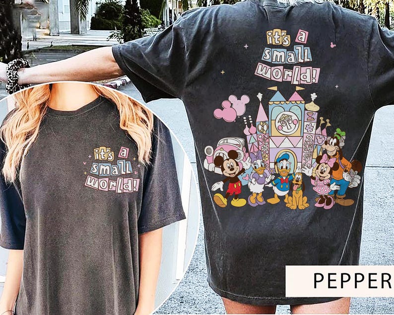 Pu&ograve; includere: T-shirt grigio scuro con la scritta "It's a Small World!" sul davanti e sul retro. Il retro presenta una grafica colorata di personaggi Disney e un castello. La maglietta &egrave; uno stile comodo e casual.