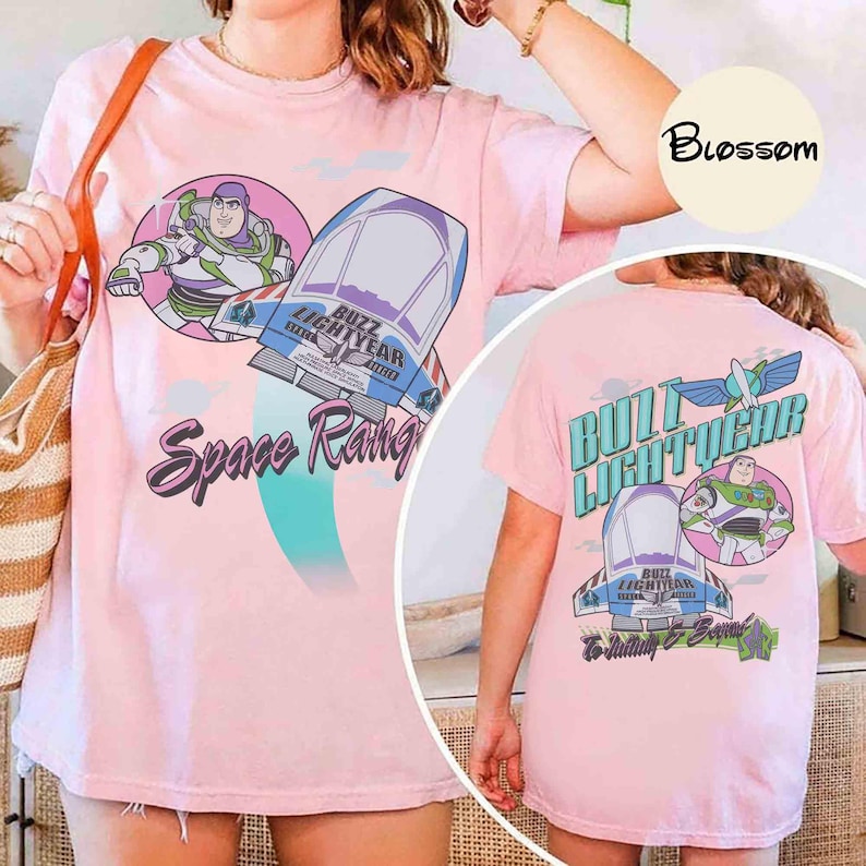 May include: A light pink t-shirt featuring a graphic of Buzz Lightyear and a spaceship with the text Space Ranger on the front, and a back graphic showing Buzz Lightyear, a spaceship, and the text Buzz Lightyear To Infinity & Beyond.