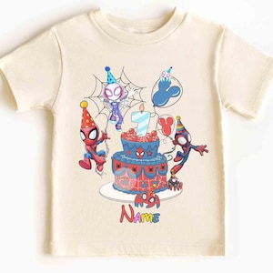 May include: Cream-colored t-shirt featuring a colorful birthday design with Spider-Man characters. The design includes a birthday cake with a lit candle, balloons, and the number 7. The word "Name" is also displayed.