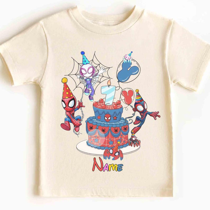 May include: Cream-colored t-shirt featuring a colorful birthday design with Spider-Man characters. The design includes a birthday cake with a lit candle, balloons, and the number 7. The word "Name" is also displayed.