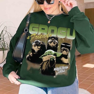May include: Dark green sweatshirt featuring the text "GROGU & Friends" in a light green font. The graphic includes Grogu and three other creatures. Below the graphic is the text "MANDALORIAN GROGU".