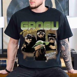 May include: Black t-shirt featuring a graphic of Grogu and friends from The Mandalorian. The design includes the text "GROGU & Friends" in green and yellow, with images of Grogu and other characters. The shirt is a crew neck.