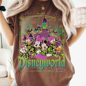 May include: Brown t-shirt with a Disney World Halloween design. The graphic shows cartoon characters, a castle, bats, and pumpkins. The words "Disneyworld" are in green and purple, with "Est. 1971" underneath.
