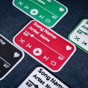 May include: A collection of rectangular embroidered patches featuring a music player interface design. Each patch displays the text Song Name and Artist Name, a progress bar, playback controls, a heart icon, and the timestamp 3:17 in white thread.