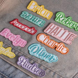 May include: A collection of embroidered name patches in various colors including yellow, teal, red, pink, orange, light blue, and purple. Each patch features a unique name: Brian, Daniel, Robert, Amanda, Hallie, Evelyn, Charlie, Oliver, Hudson, and Jaylon.