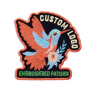 May include: Embroidered patch featuring a hummingbird with orange, blue, and black colors. The patch has the words "CUSTOM LOGO" and "EMBROIDERED PATCHES" in a curved design. The patch is outlined in orange.