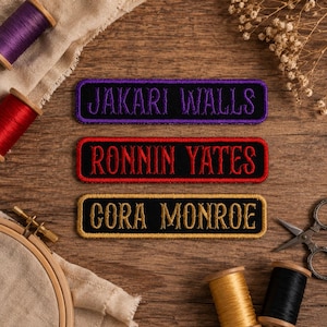 May include: Three rectangular embroidered name patches with black backgrounds. The top patch features purple text reading JAKARI WALLS, the middle patch has red text reading RONNIN YATES, and the bottom patch displays gold text reading CORA MONROE.