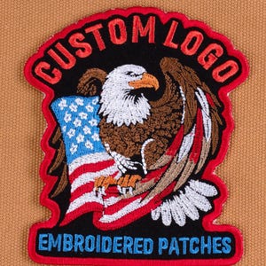 May include: Embroidered patch featuring a bald eagle with outstretched wings, clutching a US flag. The patch has a black background with red borders and text that reads "CUSTOM LOGO" and "EMBROIDERED PATCHES" in red and blue, respectively.