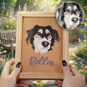 May include: Embroidered portrait of a dog named Bella, framed in light wood. The artwork features a detailed depiction of the dog's face with black, tan, and white fur. A smaller circular image of the dog is in the upper right corner.