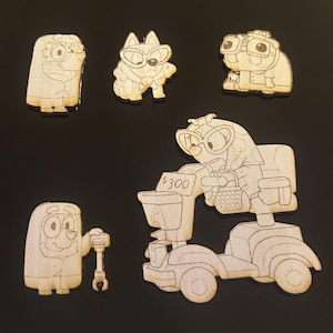 Op de afbeelding: Een verzameling onafgewerkte houten uitsparingen met stripfiguren. Eén personage zit op een scooter met de tekst "$300". Andere personages zijn een hond, een kat en een personage met een moersleutel. De uitsparingen zijn onbeschilderd.