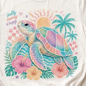 May include: White t-shirt featuring a colorful sea turtle illustration. The turtle has a rainbow shell and is surrounded by hibiscus flowers, palm trees, and the text "salty sunny & happy". The design includes a sun and ocean waves.