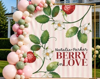 May include: A square backdrop featuring a light pink and white vertical striped pattern with strawberry plant illustrations, including red berries and white flowers. The text reads Natalie+Parker BERRY in LOVE. A balloon arch in pink and sage green.