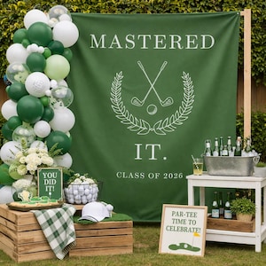 May include: A green banner with the text "MASTERED IT. CLASS OF 2026" is the backdrop for a golf-themed graduation party. Balloons, golf balls, and signs that say "YOU DID IT!" and "PAR-TEE TIME TO CELEBRATE!" complete the scene.