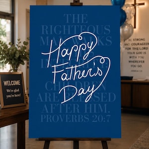 May include: A rectangular blue sign on a wooden easel featuring the white script text Happy Father's Day. Behind the script, the text The Righteous Man Walks In His Integrity; Children Are Blessed After Him. Proverbs 20:7 is printed in blue.