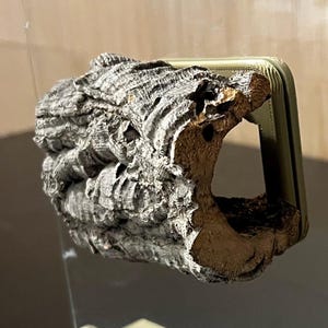 May include: A clear glass panel with a natural cork accent. The cork has a rough, textured surface and is attached to the glass with a gold-colored metal frame. The panel is supported by two beige-colored stands.