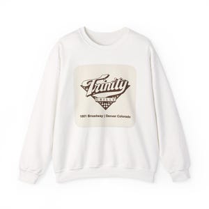 May include: White crewneck sweatshirt with a rectangular graphic. The graphic features the word "Trinity" in a stylized font, along with "GRILLE" and the address "1801 Broadway | Denver Colorado".