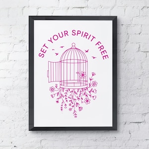 May include: A framed print with a black border features a magenta illustration of a birdcage with an open door, flowers, and birds. The text "SET YOUR SPIRIT FREE" is arched above the cage. The artwork is set against a white background.