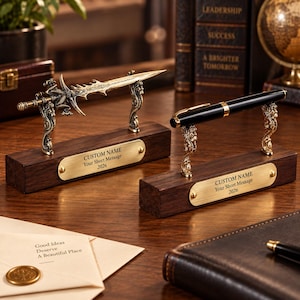 May include: Two desk accessories featuring dark wood rectangular bases with brass-colored nameplates engraved with CUSTOM NAME, Your Short Message, and 2026. One base holds a metallic dragon-themed sword, the other a black and gold ballpoint pen.