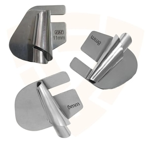 May include: Three silver-colored metal sewing machine bias tape maker attachments. Each tool features a flat base with a curved, funnel-like guide for fabric. The metal pieces are clearly marked with the sizes 11mm, 8mm, and 5mm, along with the JSC logo.