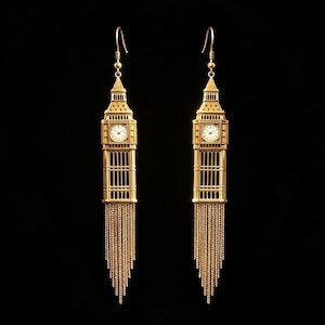 May include: A pair of gold-toned dangle earrings shaped like the Big Ben clock tower. Each earring features a detailed architectural structure with a white clock face and a long, delicate fringe of fine gold chains hanging from the base.