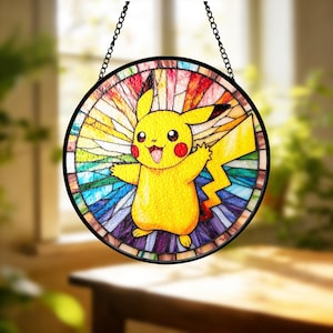May include: A round stained glass window featuring Pikachu from Pokémon. The yellow character has red cheeks and is surrounded by a colorful, geometric background. The window is framed in black and hangs from a chain.