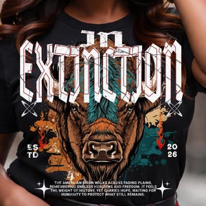 Op de afbeelding: Zwart t-shirt met het woord "Extinction" in een opvallend lettertype boven een gedetailleerde illustratie van een bizon. Het shirt toont ook "ES TD", de nummers "20 26" en een paragraaf over de Amerikaanse bizon.