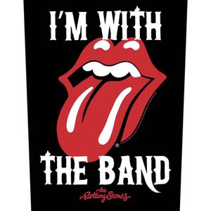 Puede incluir: Gráfico negro con las palabras "I'M WITH THE BAND" en blanco, sobre un logotipo de labios y lengua rojos. El logotipo de los Rolling Stones está en la parte inferior en escritura roja. Un diseño clásico de rock and roll.