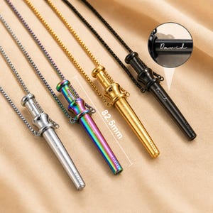 Peut inclure: Quatre pendentifs cylindriques sur chaînes carrées aux finitions argentée, arc-en-ciel, dorée et noire. Chaque pendentif présente un sommet évasé et un corps effilé avec un petit trou à l'extrémité. Une ligne de mesure indique 82,5 mm. Le pendentif noir porte le nom gravé David.