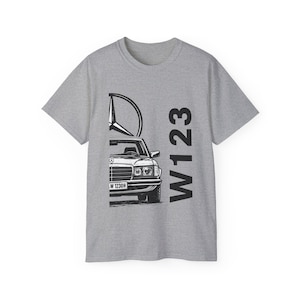 Peut inclure: T-shirt gris avec une illustration en noir et blanc d'une voiture classique, la Mercedes-Benz W123, et le logo Mercedes. Le texte "W123" est imprimé verticalement sur le côté droit du t-shirt.