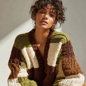 May include: A chunky knit cardigan in a patchwork design. The sweater features blocks of brown, olive green, and cream colors. The open front cardigan has long sleeves and a relaxed fit, perfect for layering.