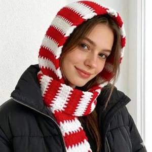 May include: A red and white striped knitted hood and scarf set. The hood and scarf are made of a thick, textured yarn and are designed to keep the wearer warm. The scarf is long and can be wrapped around the neck for added warmth.