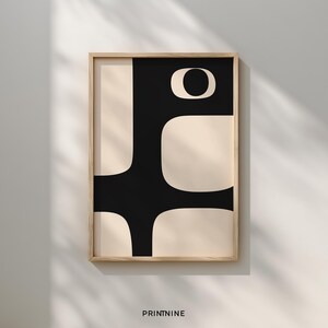 Könnte beinhalten: Abstrakter Kunstdruck in einem Holzrahmen. Das Kunstwerk zeigt ein schwarzes geometrisches Design auf cremefarbenem Hintergrund. Das Design umfasst eine große schwarze Form mit abgerundeten Ecken und ein kreisförmiges Element. Der Text "PRINTNINE" befindet sich unten.