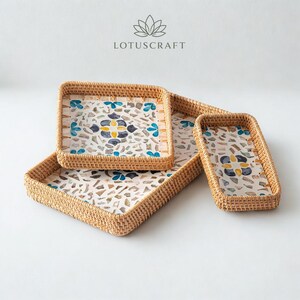 May include: Three woven rattan trays with light brown natural fibre borders and white interior bases featuring a mosaic pattern of blue, yellow, and grey stone-like fragments. The text LOTUSCRAFT is printed above the trays with a lotus icon.