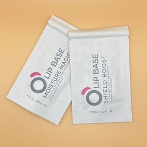 Può includere: Due bustine di carta bianca di prodotti per la base labbra. Una recita "Moisture Magic" e l'altra "Shield Boost". Ogni bustina ha un design rosa e grigio con la scritta "LIP BASE". Ogni bustina è da 3,5 g / 0,12 fl oz.