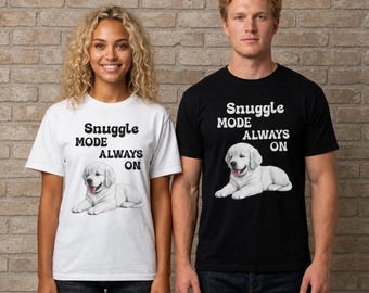 May include: A white t-shirt and a black t-shirt, each featuring a graphic of a golden retriever puppy lying down with its tongue out. Above the puppy, the text reads "SNUGGLE MODE ALWAYS ON" in a bold, rounded, dark-colored sans-serif font.