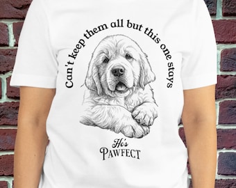 May include: A white short-sleeved t-shirt featuring a black and white line art illustration of a golden retriever puppy. The text surrounding the puppy reads, Can't keep them all but this one stays, and below the puppy, it says, He's PAWFECT.