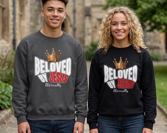 May include: A charcoal gray sweatshirt and a black sweatshirt, both featuring a gold crown graphic above the white and red text that reads BELOVED BY JESUS and the word Eternally in a cursive script font centered below the main text.