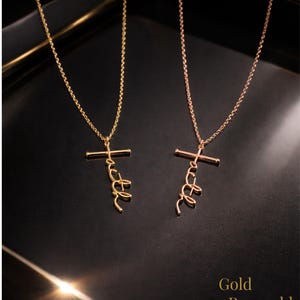 May include: Two gold necklaces with a cross pendant and the word "faith" in a cursive font. The necklaces are displayed on a black surface. The text "Gold Rosegold" is at the bottom.