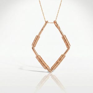 May include: Rose gold necklace featuring a geometric diamond-shaped pendant. The pendant has a wire-wrapped design on the diagonal bars, and is suspended from a delicate chain. The necklace is displayed on a white surface.