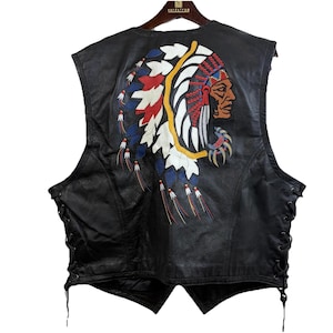 May include: Black leather vest with a Native American chief design embroidered on the back. The design features a chief's profile with a colourful headdress in red, white, blue, and yellow. The vest has side laces.