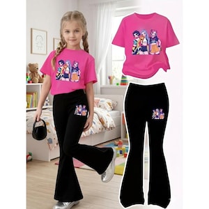 May include: A young girl wearing a pink t-shirt and black flared pants. The shirt and pants feature a colorful graphic of three cartoon characters. The outfit is displayed on a white background, with a matching set of the shirt and pants.