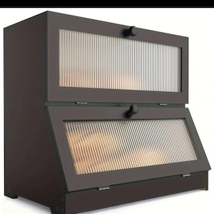 以下が含まれることがあります： リブガラスのドアと黒いノブが付いた、濃い茶色の2段のパンボックス。上のドアは長方形で、下のドアは角度が付いています。木製で、シンプルでモダンなデザインです。