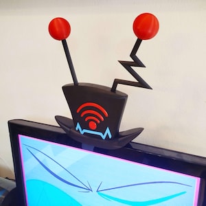 May include: A black TV antenna topper with red spheres and a Wi-Fi symbol. The antenna has a zig-zag design and is placed on top of a television screen. The Wi-Fi symbol is red and orange.