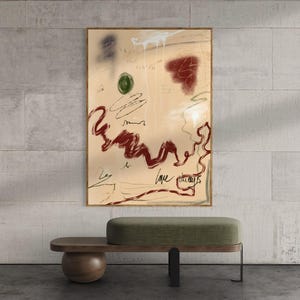 Puede incluir: Impresión artística abstracta en un marco dorado con marcas rojas, verdes y blancas sobre un fondo beige. Debajo, un banco de madera con asiento tapizado verde y base redondeada marrón oscuro.