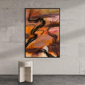 Könnte beinhalten: Abstrakter Kunstdruck in einem schwarzen Rahmen. Das Kunstwerk zeigt kräftige schwarze Pinselstriche auf einem Hintergrund aus Orange-, Braun- und Rosatönen. Der Text "built for love" ist unten rechts sichtbar. Ein kleiner, weißer, geometrischer Beistelltisch befindet sich im Vordergrund.