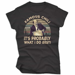 May include: Black t-shirt featuring a retro design with the text "FAMOUS CHILI" above an image of a man holding a pot. Below the image, the text reads "IT'S PROBABLY WHAT I DO BEST!"