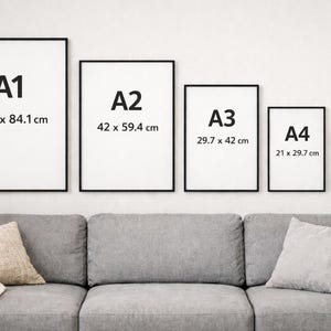 May include: Five framed art prints of varying sizes (A1, A2, A3, A4, A5) are displayed on a white wall above a gray sofa. The prints have black frames and white backgrounds with the size labeled in centimeters.