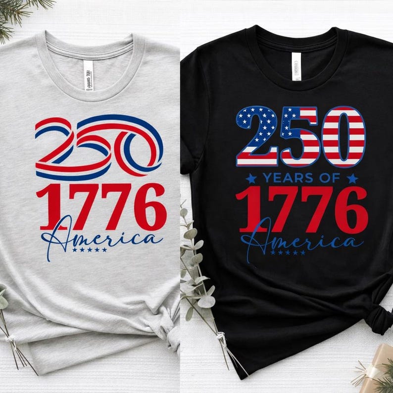 May include: Two t-shirts, one light gray and one black, each with a patriotic design. The design features the number "250" in red, white, and blue, the year "1776" in red, and the word "America" in blue.