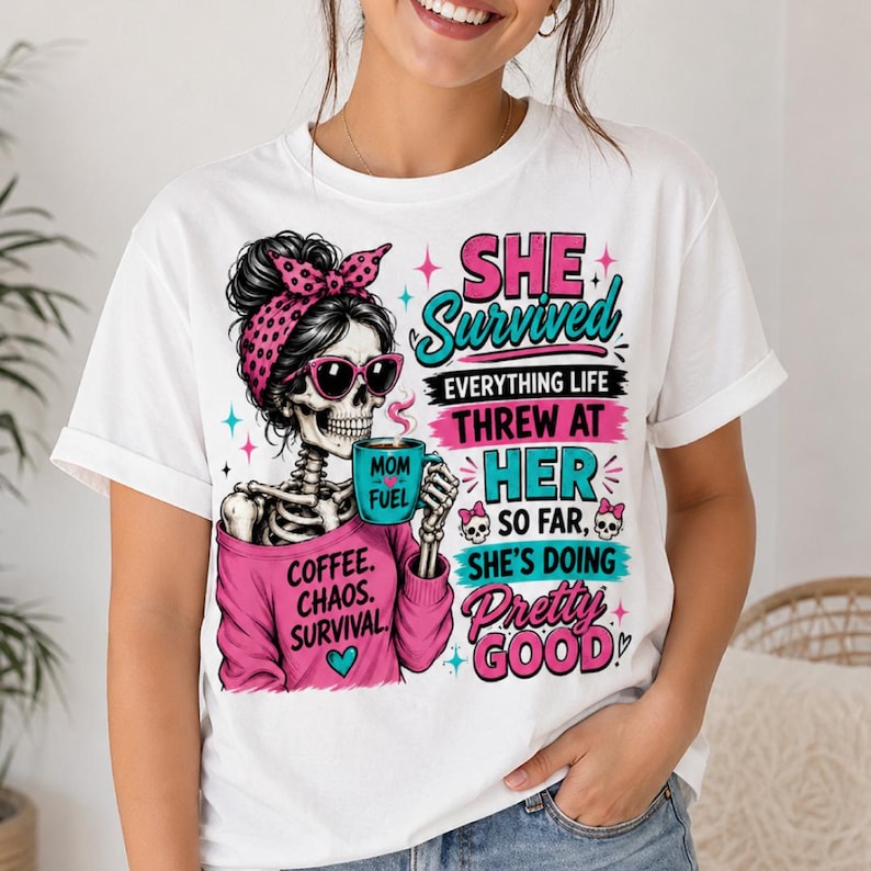 May include: White t-shirt with a skeleton graphic wearing sunglasses and a pink headband, holding a coffee mug. Text reads "SHE Survived" and "Coffee. Chaos. Survival."