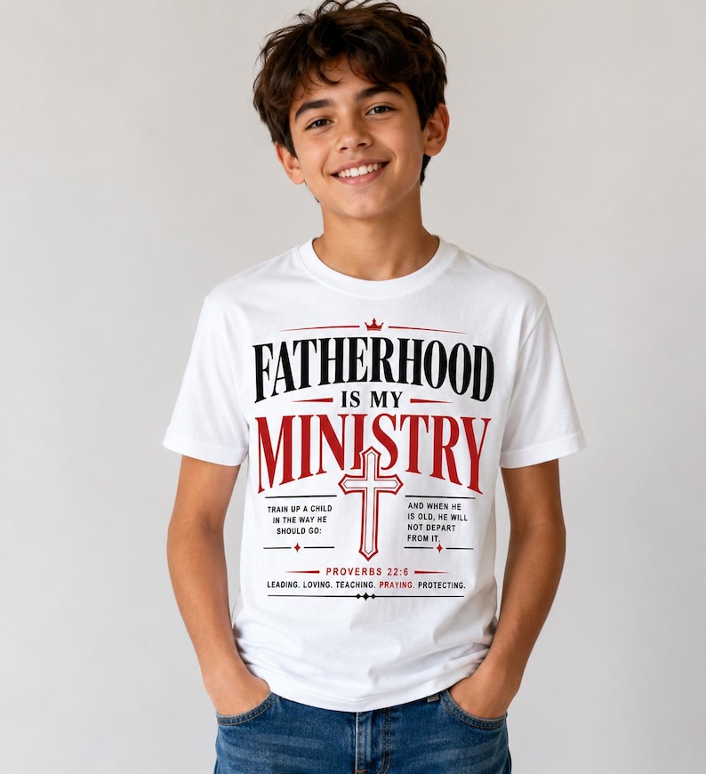 Peut inclure: T-shirt blanc avec l'inscription "FATHERHOOD IS MY MINISTRY" en noir et rouge. Le t-shirt pr&eacute;sente une croix et le verset biblique Proverbes 22:6. Le t-shirt contient &eacute;galement les mots "LEADING. LOVING. TEACHING. PRAYING. PROTECTING."